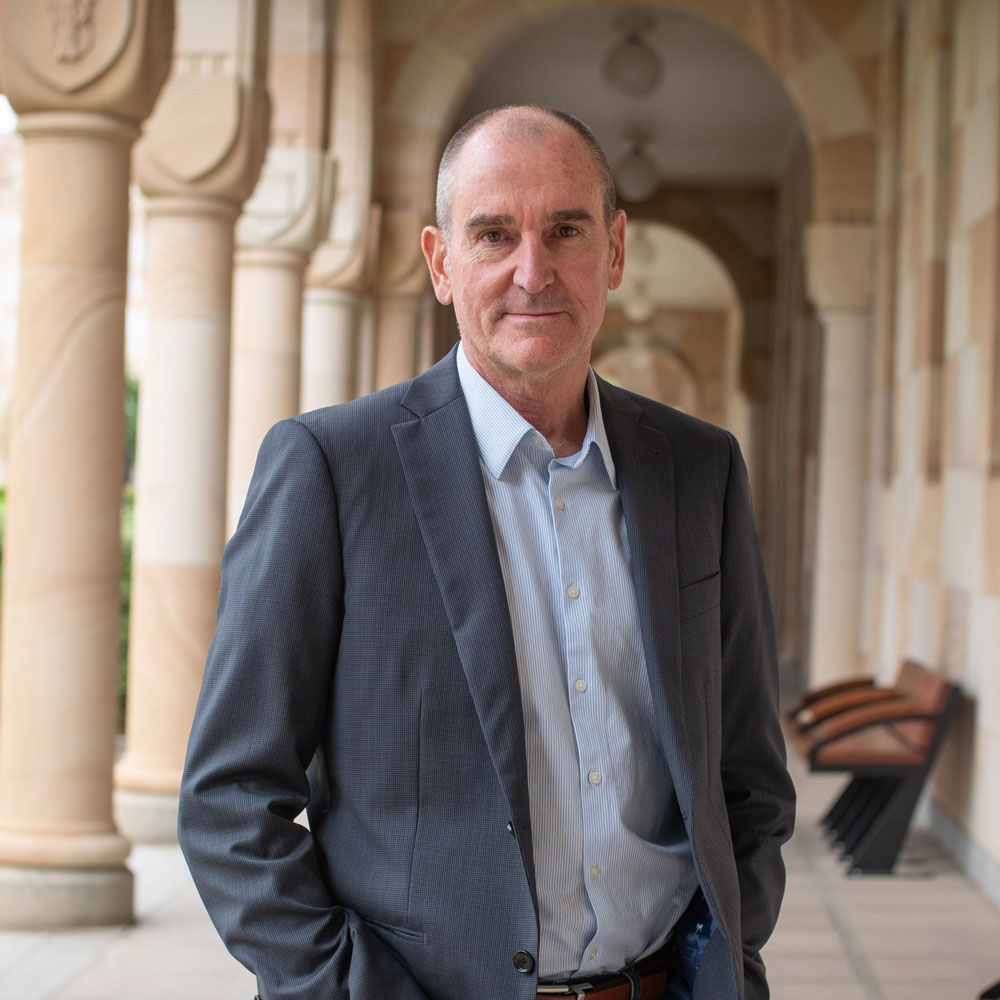 Headshot of Prof Michael Udvardi suited and in the UQ Great Court sandstone 