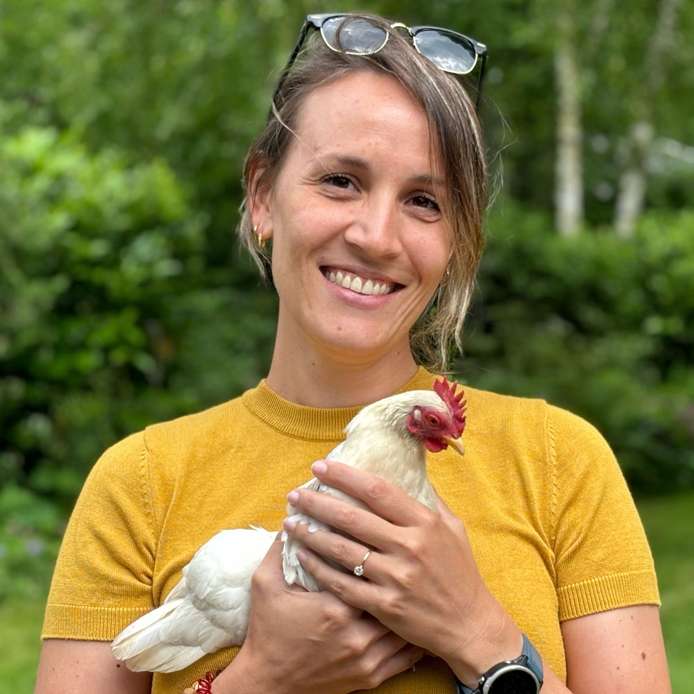 Dr Mila Miejer holding a chicken and smiling at the camera