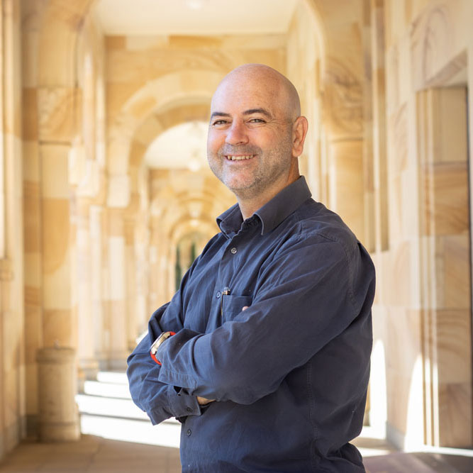 Prof Eugeni Roura with arms crossed across his chest standing side on in UQ's Great Court