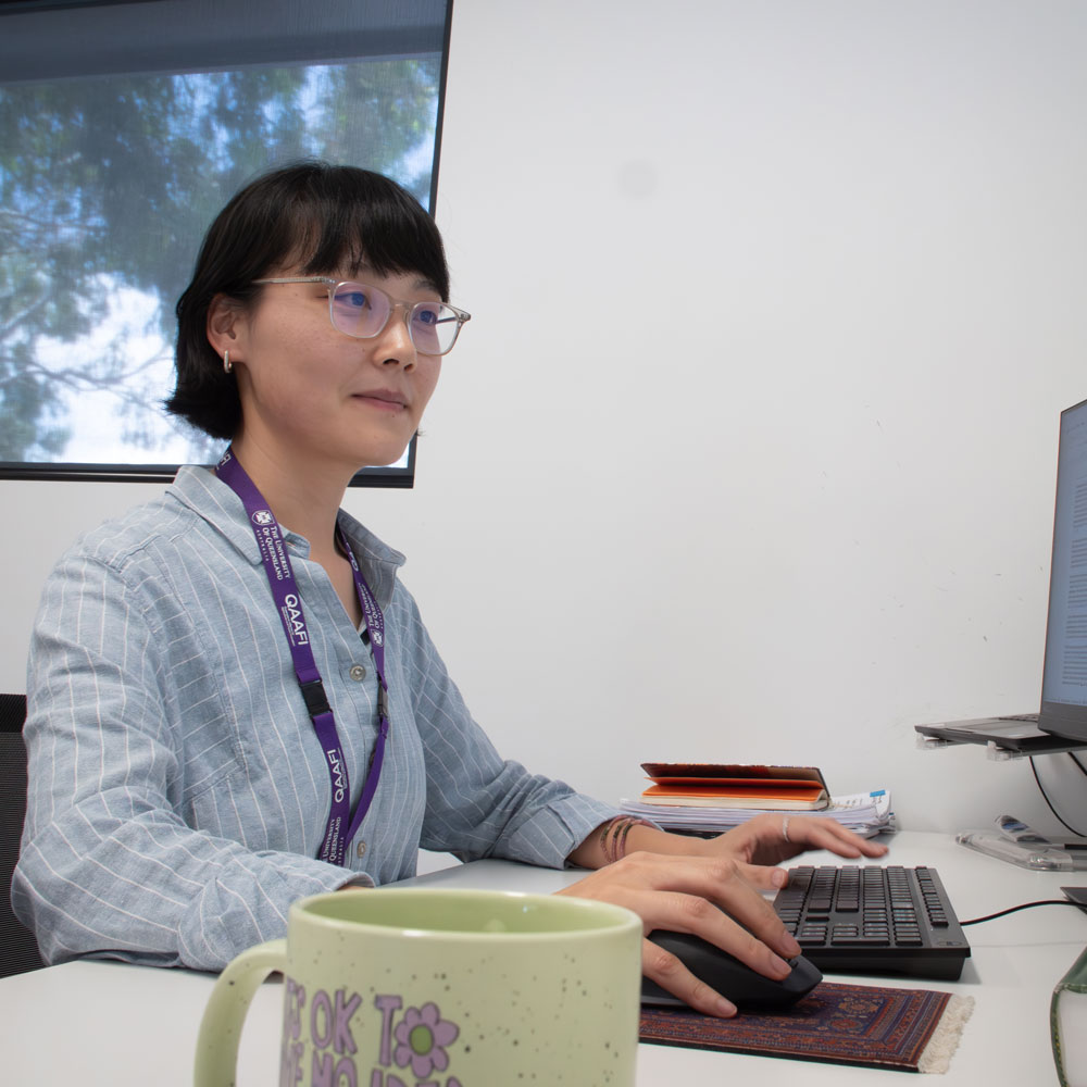 Dr Dongxue zhao sitting at a desk in front of a computer screen 