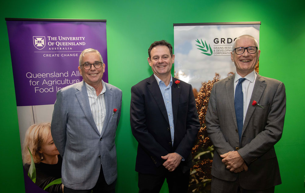 Three men standing in front of two banners promoting QAAFI and GRDC 
