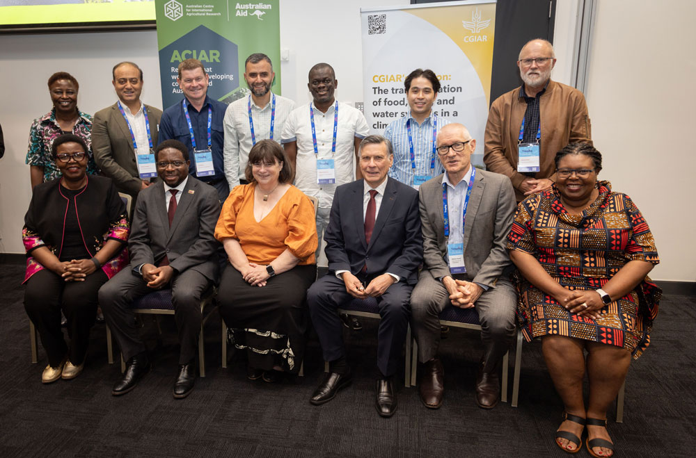 Group of people some sitting and standing with ACIAR and CGIAR banners behind