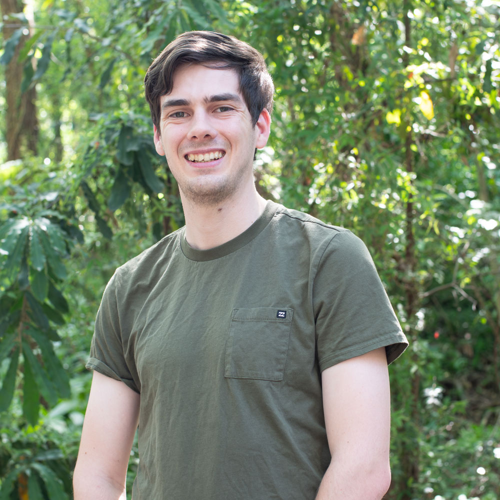 Headshot of man in khaki t-shirt with green background