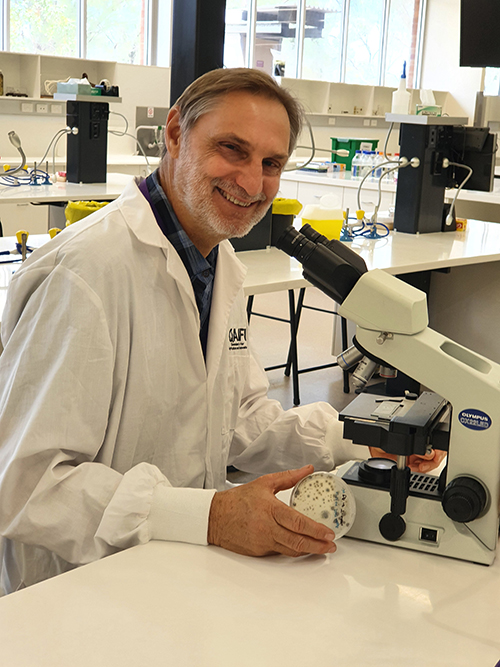 Prof Louw Hoffman sitting at a microscope in a laboratory