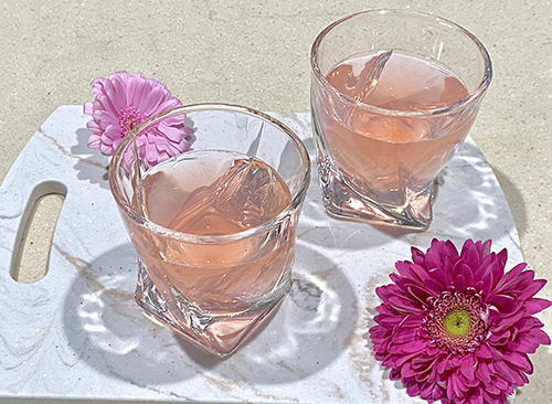 Sample of the beverage in glasses with flowers around them