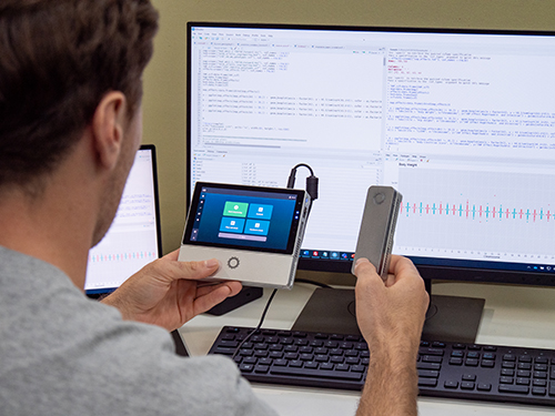 Harry Lamb holding MinION device in front of computer uploading data 