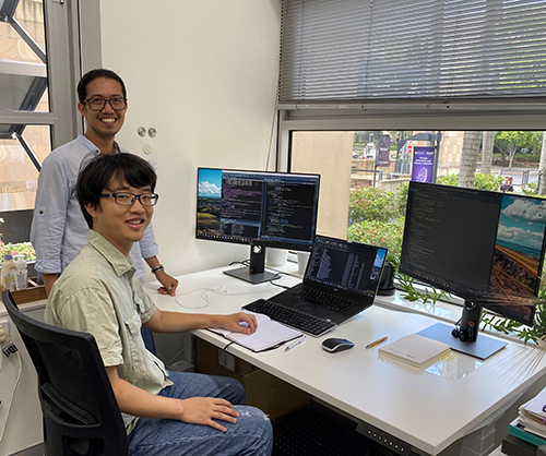 Dr Eric Dinlasan and Phd candidate Chensong Chen at a computer. Chen is sitting and Eric is standing behind him