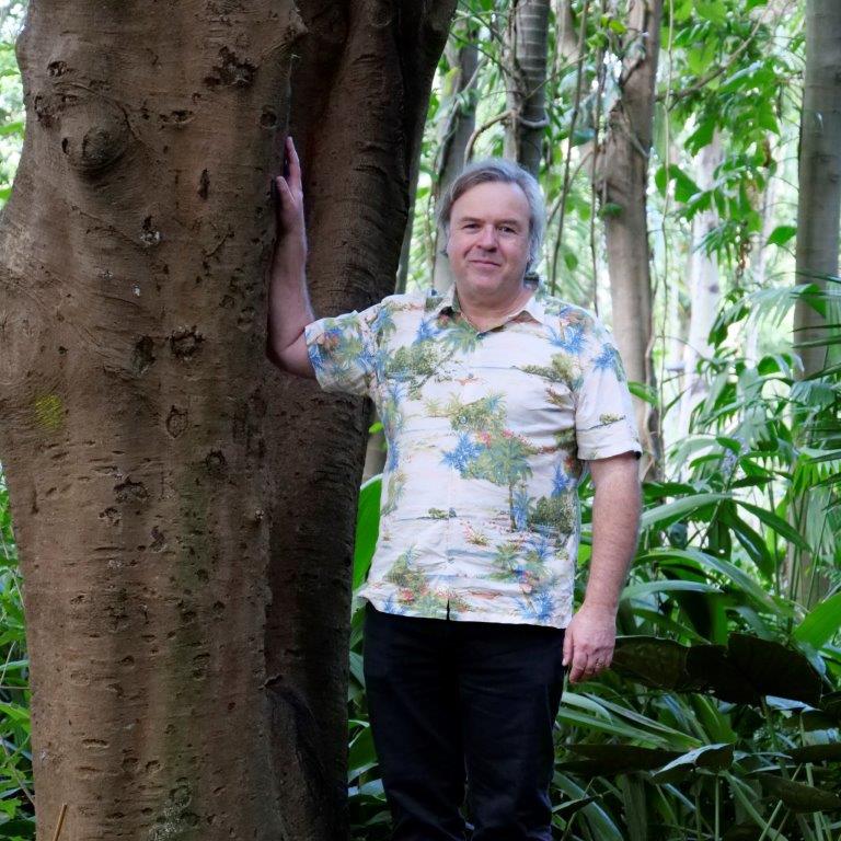 A/Prof Craig Hardner, with his hand against a large tree trunk