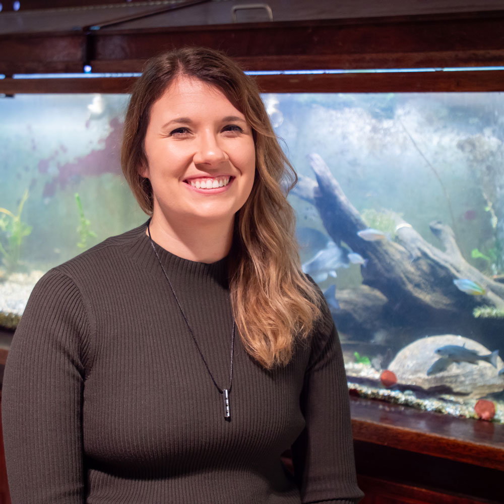 Jessica Hintzsche with an aquarium filled with fish behind her