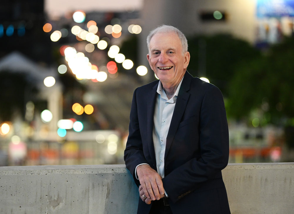 Prof Robert Henry leaning against a wall with skyline behind