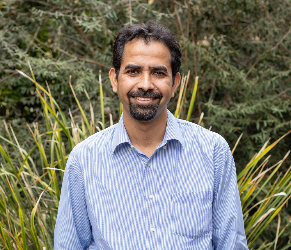 Headshot of Sudhir Yadav with greenery behind him