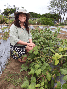 Shanice kneeling in a field of crops 