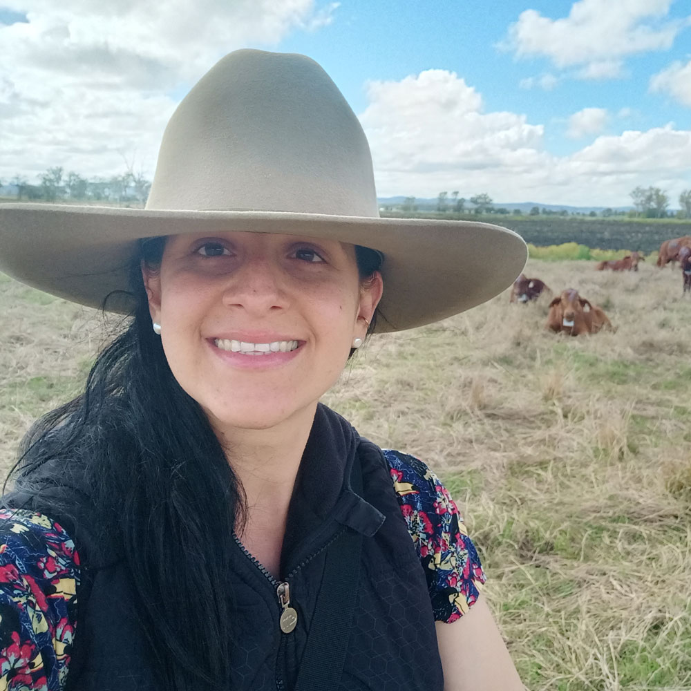 Headshot of Tamara Freitas-Kirk in the field with cattle behind her 