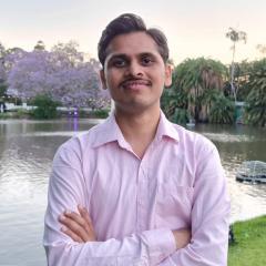 Dr Onkar Nath by the UQ lakes, with blooming jacaranda behind him
