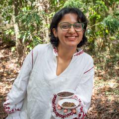 Sera Jacob holding wattleseed with greenery behind 