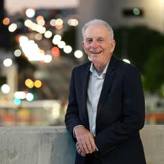 Profesor Robert Henry leaning against a ledge with city lights behind him