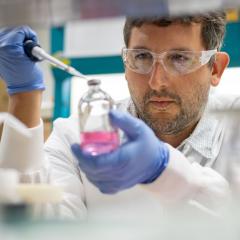 Estoban in the lab, holding a beaker and a pipette