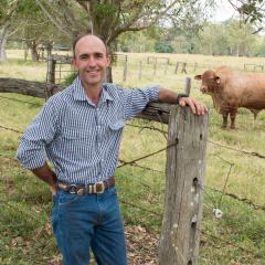 Kieren McCosker leaning against a fence post in a paddock