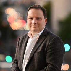 Professor Paul Gauthier headshot with night lights behind him