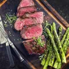 Barbecue Wagyu Point Steak with green Asparagus as close-up on burnt cutting board