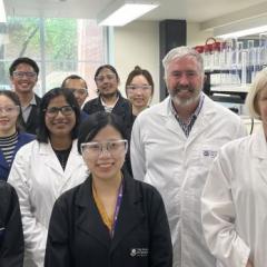 Professor Nidhi Bansal, Senator Anthony Chisholm and Vice-Chancellor Professor Deborah Terry (white coats, L-R) with UQ postgraduate students.