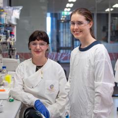 Rebecca Degnan and Dr Anne Sawyer in the laboratory, both in white coats and protective glasses. Image: Megan Pope
